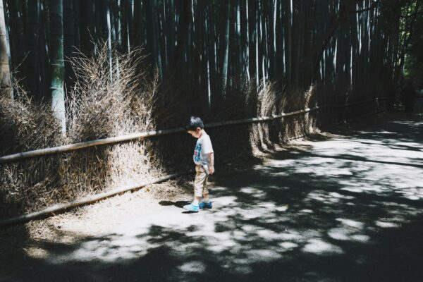 boy wearing white top standing on gray concrete floor