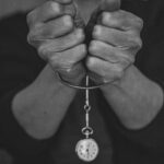 grayscale photo of person holding round pendant necklace