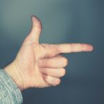 person's left hand doing gun sign