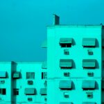 a tall white building with many windows and a sky background